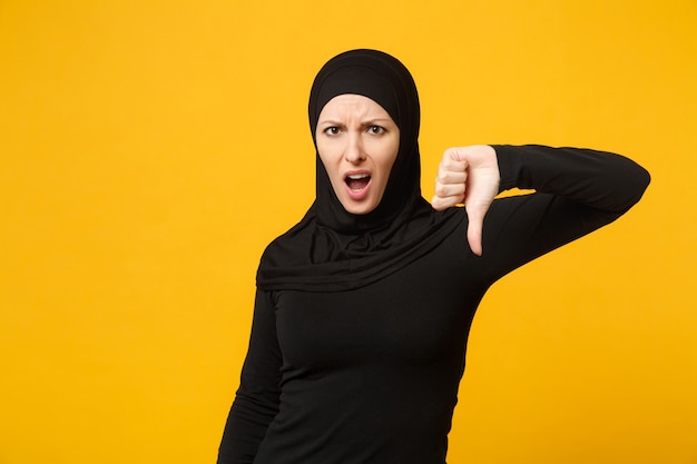 Triest boos huilende verwarde jonge Arabische moslimvrouw in hijab zwarte kleding poseren geïsoleerd op gele muur portret. Mensen religieuze islam levensstijl concept.