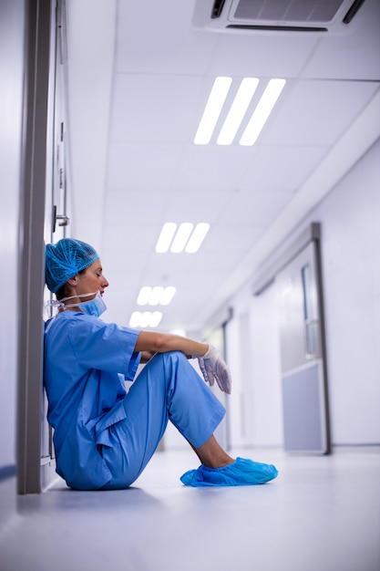 Triest chirurg zittend op de vloer in de gang