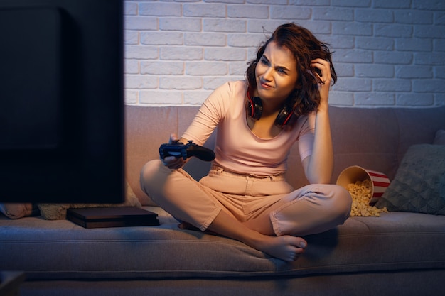 Triest gamermeisje dat videogames speelt op de console in haar appartement