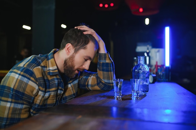 Triest jonge man zit aan toog in pub Boos man drinkt alcohol vanwege problemen op het werk