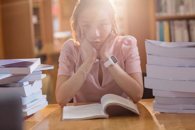 Triest jonge vrouw studeren in bibliotheek