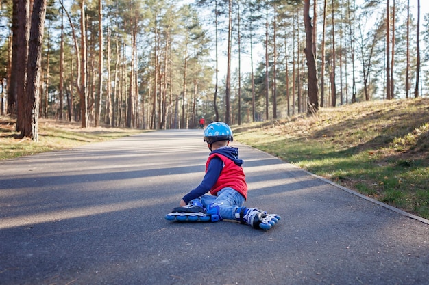 Triest kind in sport helm rijden op rolschaatsen in het park