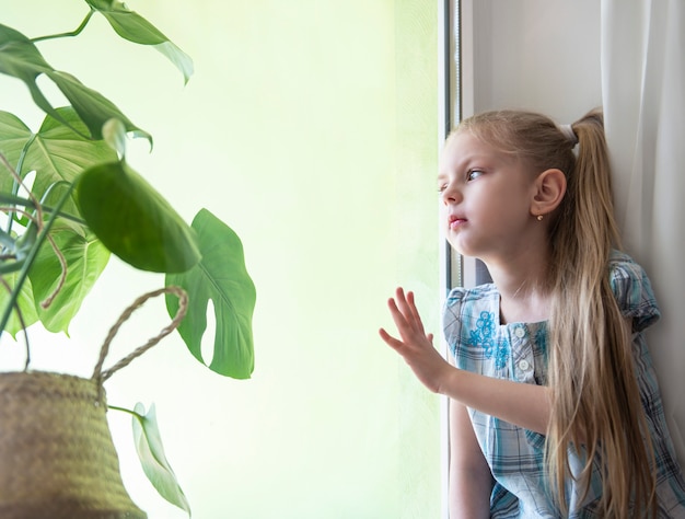 Triest kind meisje bij het raam