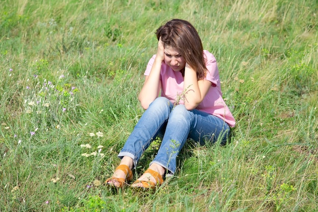 Triest meisje op groen gras op het platteland.