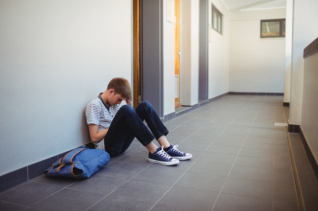 Triest schooljongen zit in de gang