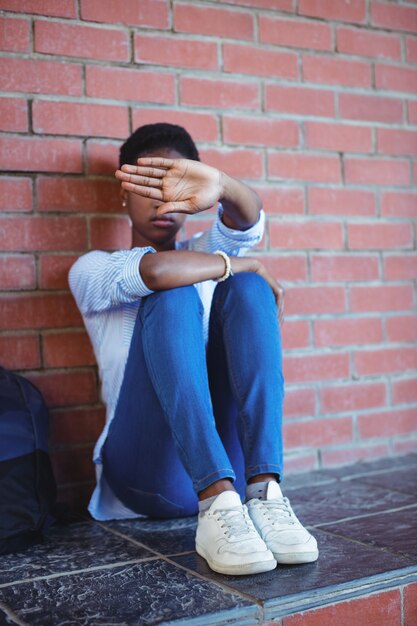 Triest schoolmeisje dat haar gezicht behandelt met hand