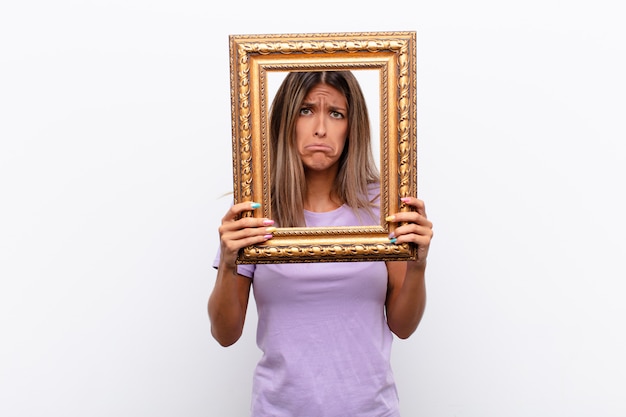 Triest vrouw kijkt door een klassieke gouden frame