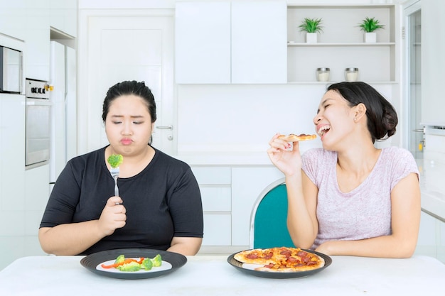 Trieste dikke vrouw eet salade terwijl ze bespot wordt door vriend