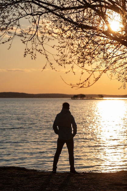 Foto trieste en contemplatieve persoon in de buurt van het meer