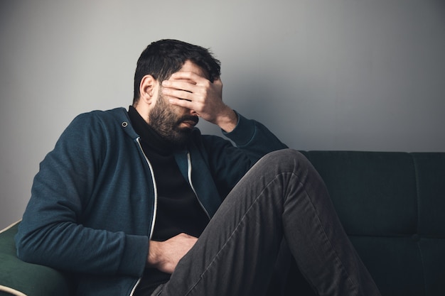 Trieste man bedekte zijn gezicht zittend op de bank