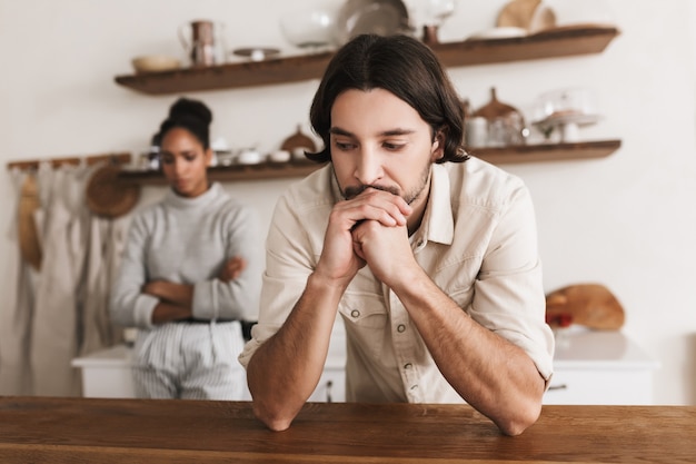 Foto trieste man met baard, bedachtzaam op tafel leunend