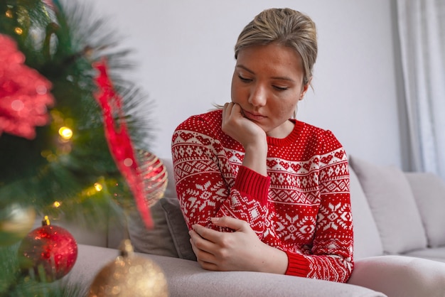 Trieste vrouw door de kerstboom overweegt