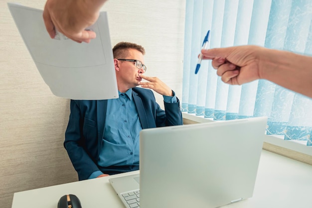 Foto trieste zakenman in een pak zit op kantoor en kijkt naar de documenten sluiting van een contract met de baas onwil om een contract te ondertekenen ontslag van een werknemer