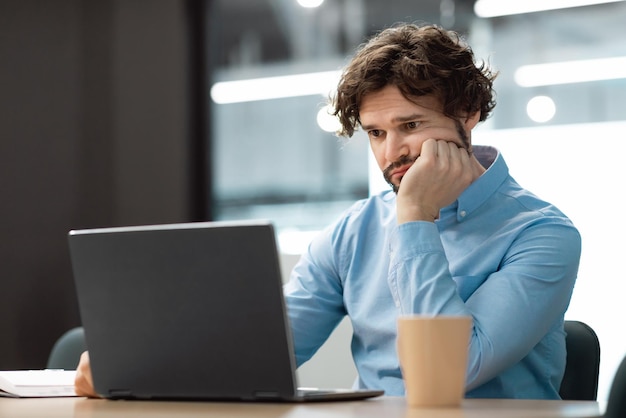 Trieste zakenman met behulp van laptop zit aan bureau