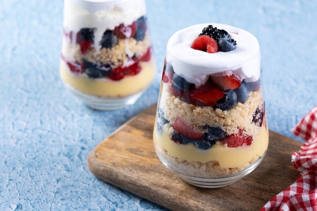 Trifle dessert with berries and cream on blue background