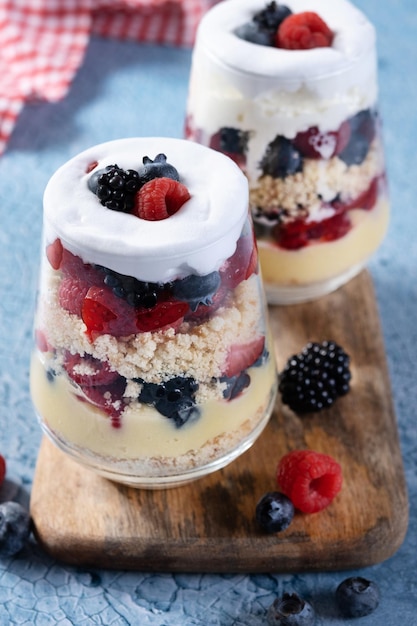 Dessert di zuppa inglese con frutti di bosco e panna su sfondo blu