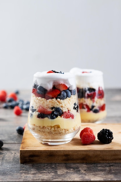 Trifle dessert with berries and cream on wooden table