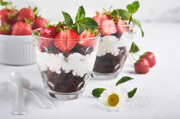 Trifles Brownies verse aardbeien en mascarpone crème geserveerd in lagen op glas op witte achtergrond Gedeelte desserts Geen gebakken brownie cheesecake met verse bessen in een glas