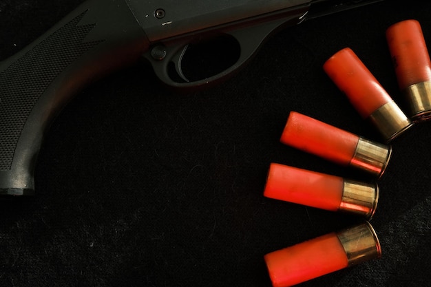 黒い背景に赤い稲妻が描かれたライフルの引き金 黒い表面に散弾銃の砲弾がある 12 ゲージの滑腔砲用の弾薬 狩猟用の弾薬 暗い背景