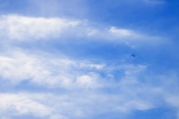 Foto trillende blauwe bewolkte hemel met ver weg vliegend vliegtuig