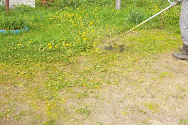 Trimmer maait gras in het veld in de zomer