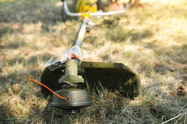 Trimmer na het maaien van grasclose-up Benzinepomp op het gras met veiligheidsbril Landscaping en landschapsarchitectuur van het tuinperceel gazonverzorging