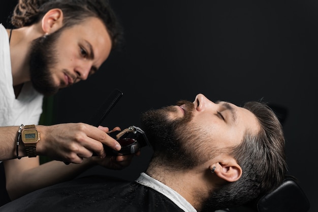 Trimming the beard with a shaving machine. Advertising for barbershop and men's beauty salon.