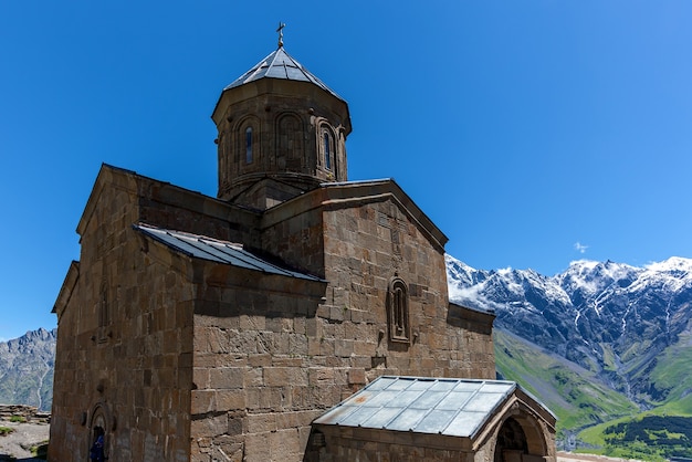 Trinity Church op de berg tegen de achtergrond van rotsen in het dorp Gergeti aan de Georgische militaire snelweg