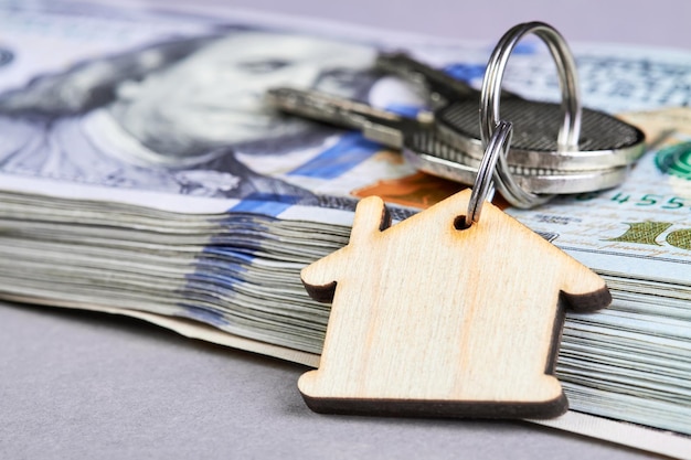 Trinket in the form of a wooden house with the keys to the apartment on the blue background