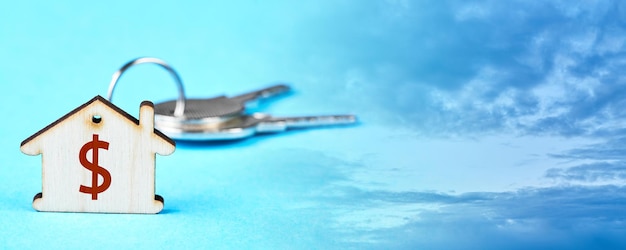 Trinket with the keys to the apartment on the blue background with sky and clouds