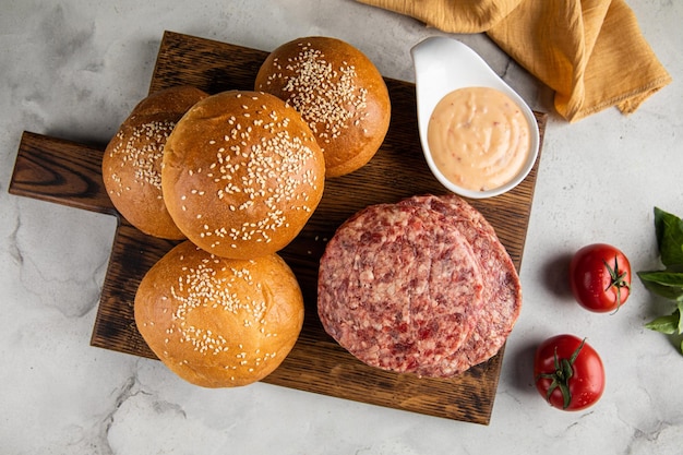 Trio burger and tomato on a wooden plate on top of a checkered cloth table