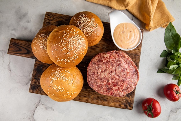 Trio hamburger e pomodoro su un piatto di legno sopra un tavolo di stoffa a scacchi