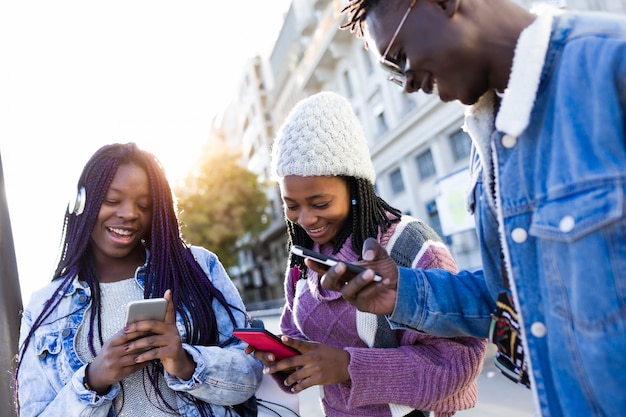 Trio vrienden die mobiele telefoon in de straat gebruiken.