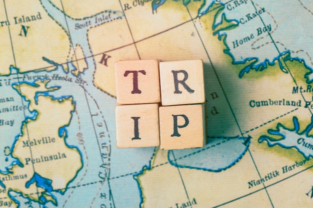 Trip word written in wooden blocks on a vintage travel map