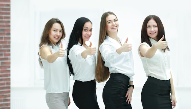 Triumphant business team holding thumbs up teamwork