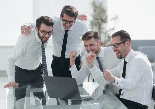 Triumphant business team looking at the laptop screenstartup