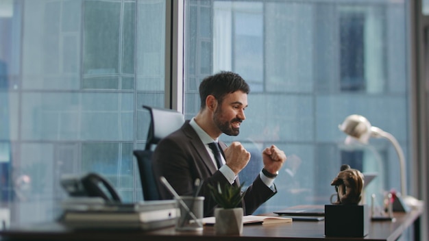 triumphing business man expressing happiness looking laptop screen in office
