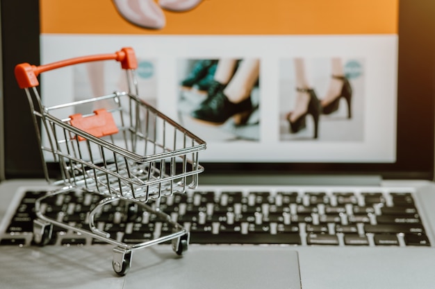 Trolley winkelwagentje met computer laptop op een tafel. Concept voor online winkelen of e-commerce via internet voor bescherming tegen de ziekte van Coronavirus COVID-19