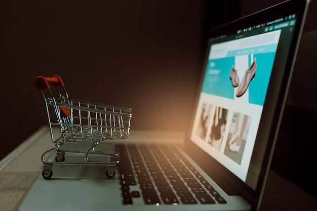 Trolley winkelwagentje op een laptop toetsenbord. Ideeën voor online winkelen of e-commerce via internet.