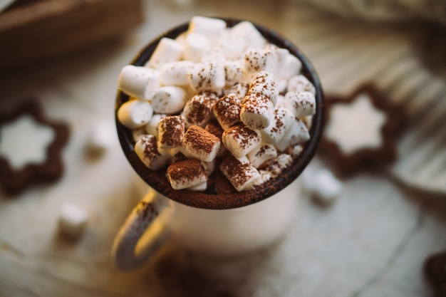 Troostende kerstmok warme chocolademelk met marshmallow en koekjes met gezellige lichtjes