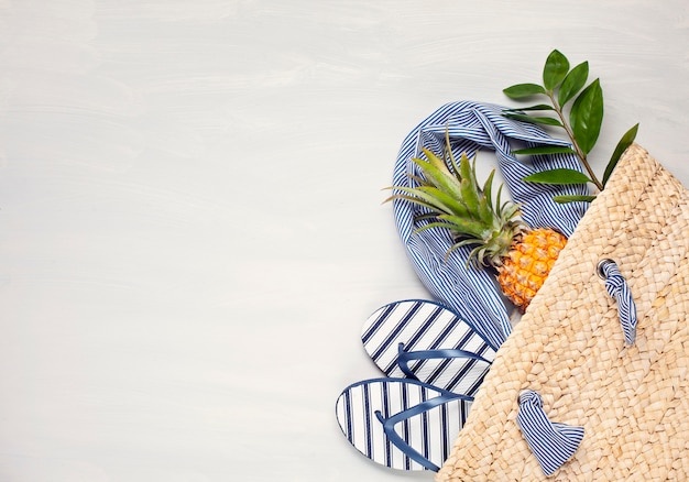 Vista dall'alto di accessori spiaggia tropicale con borsa estiva paglia e infradito