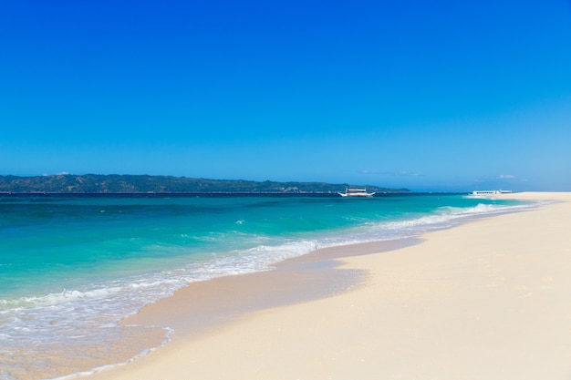 Foto spiaggia tropicale e bellissimo mare con barche. cielo azzurro con nuvole sullo sfondo.