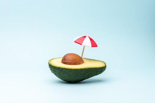 Концепция тропического пляжа из фруктов авокадо и зонтика от солнца