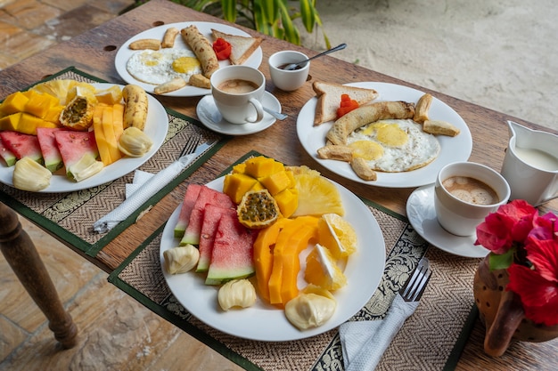 Тропический завтрак из фруктов, кофе, омлета и бананового блина на двоих на пляже у моря в ресторане отеля, остров занзибар, танзания, африка, крупным планом