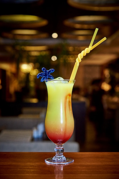 Cocktail tropicale sul bancone bar su uno sfondo sfocato scuro.