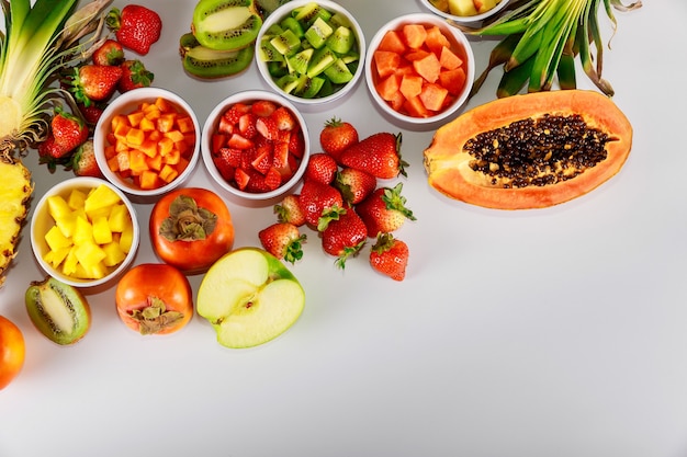 Tropical colorful whole and cut fruits on white background.