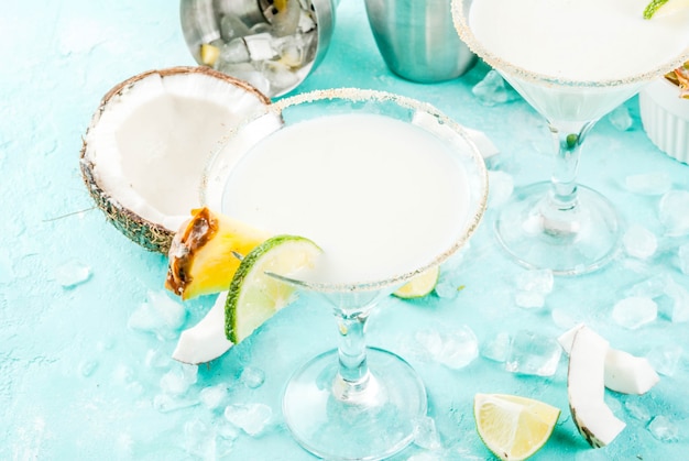 Тропический напиток Frozen Coconut Pineapple Margaritas с замороженным соком ананаса из пина-колады, текилы и лайма на голубом фоне