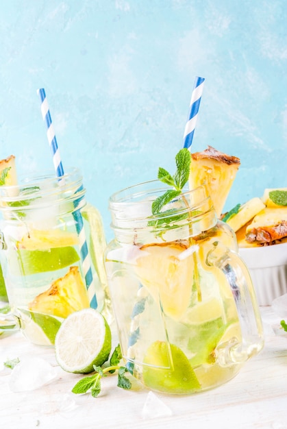 Tropical drink Pineapple mojito or lemonade with fresh lime and mint light blue background 