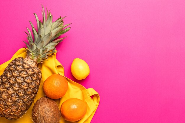 Tropical fresh exotic fruits with a yellow cotton bag on a yellow background. Flat lay. Food concept.