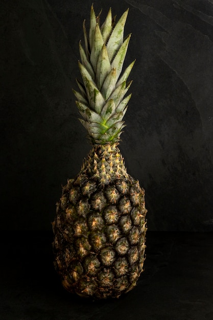 Photo tropical fruit: isolated pineapple, over black stone background.